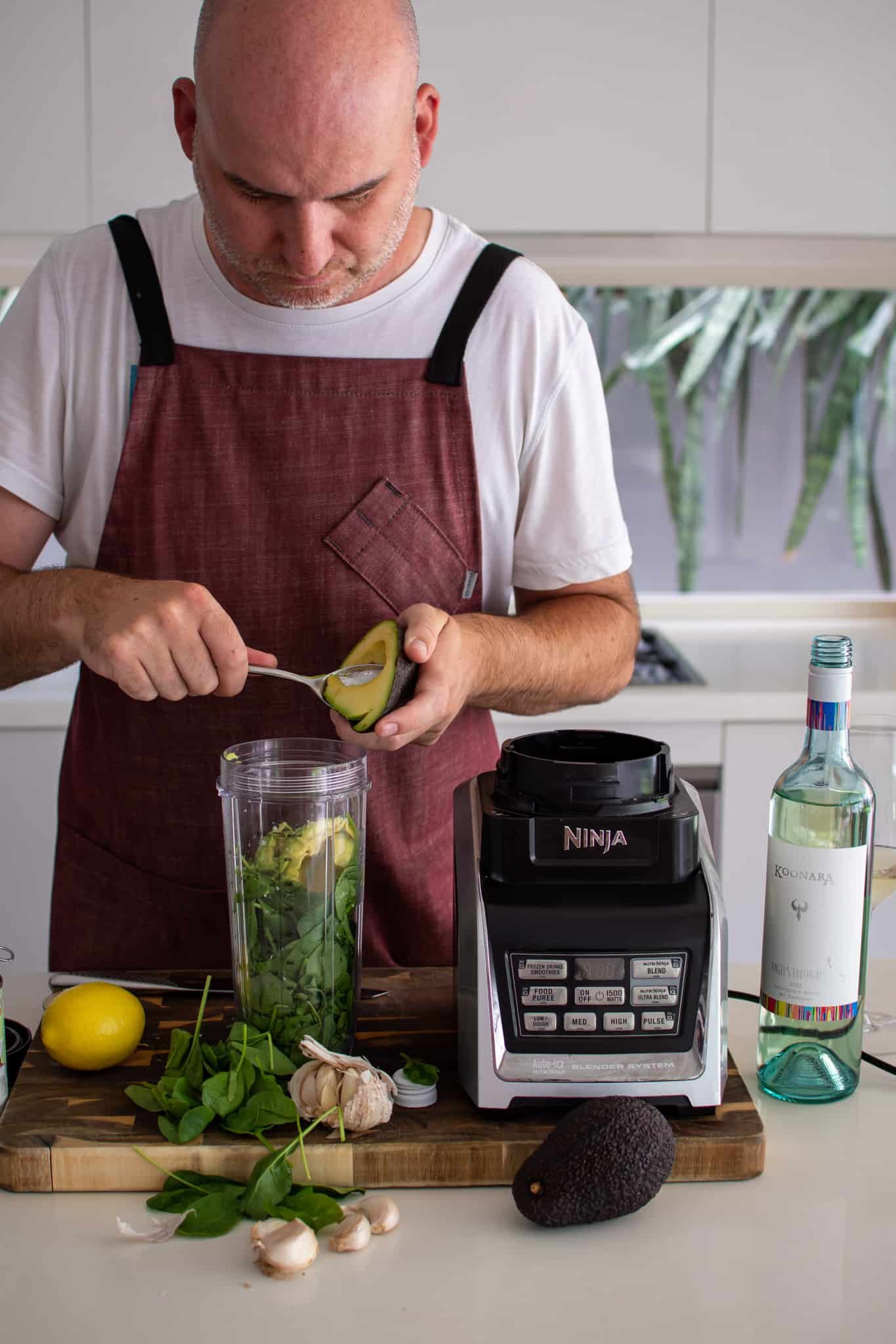 someone in the kitchen making sauce for avocado pasta