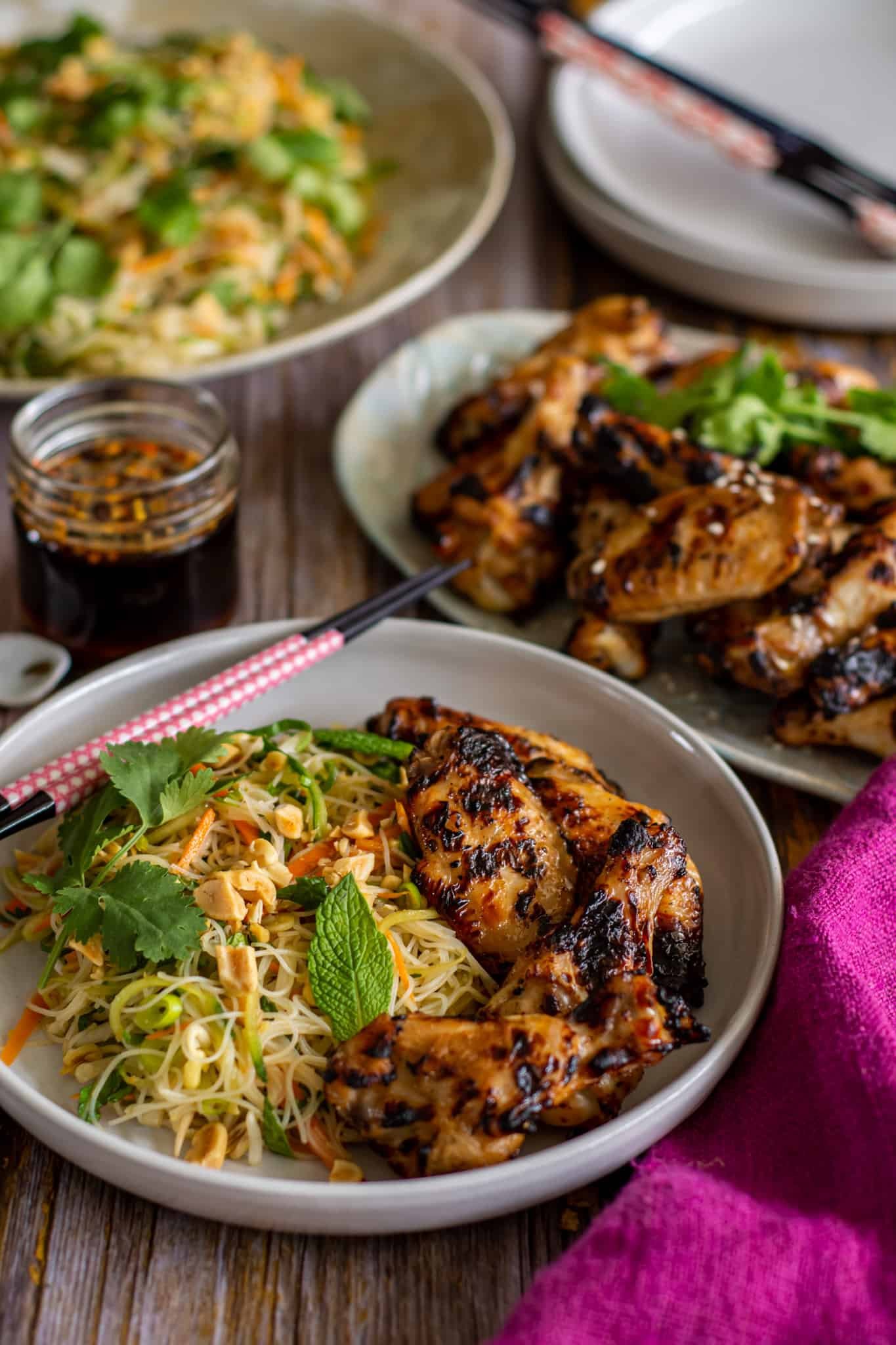table setting with a plate of chicken vermicelli noodle salad with chicken on  a plate in background