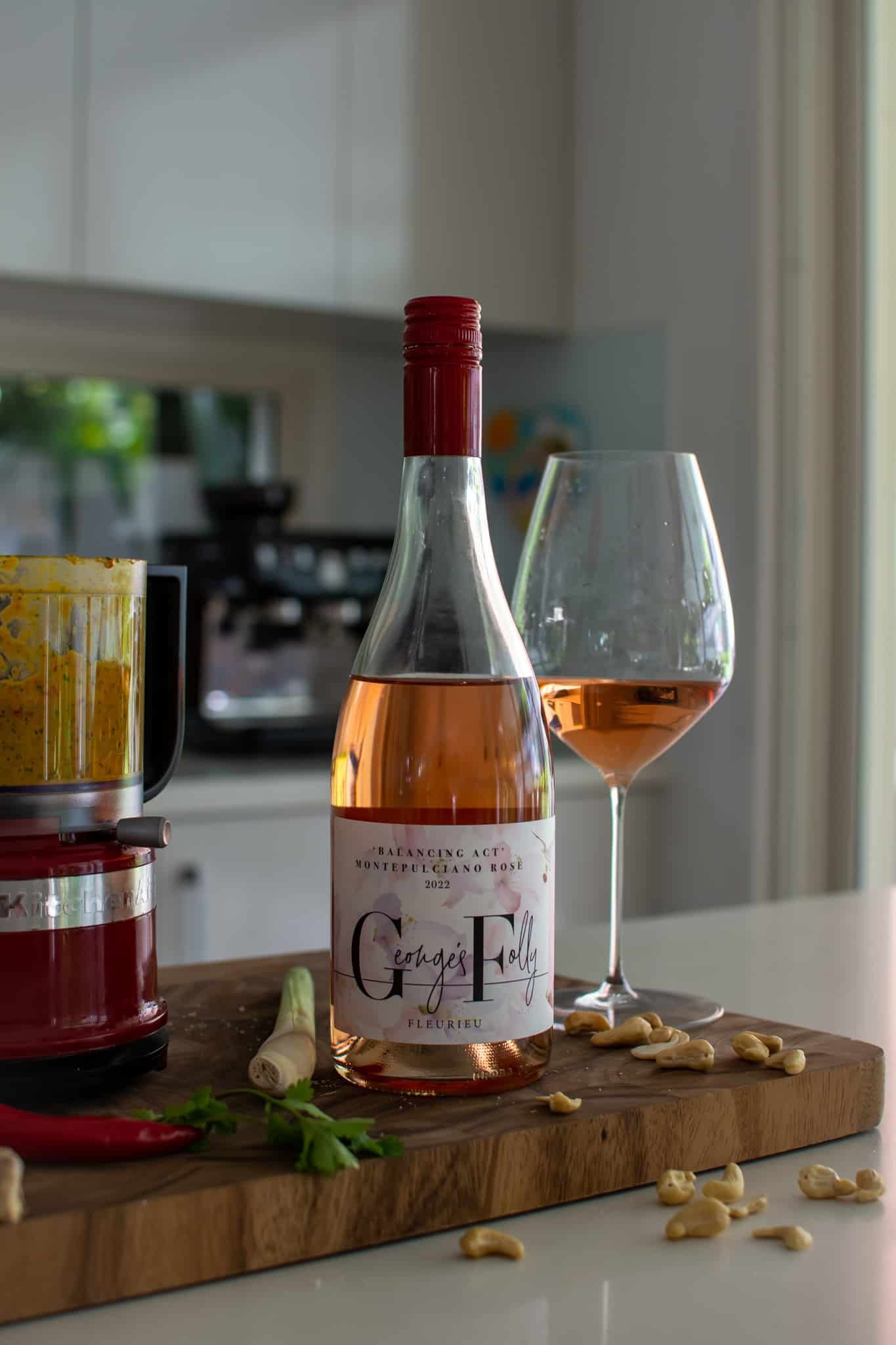 Rose wine on kitchen counter with laksa paste ingredients on chopping board and paste in food processor