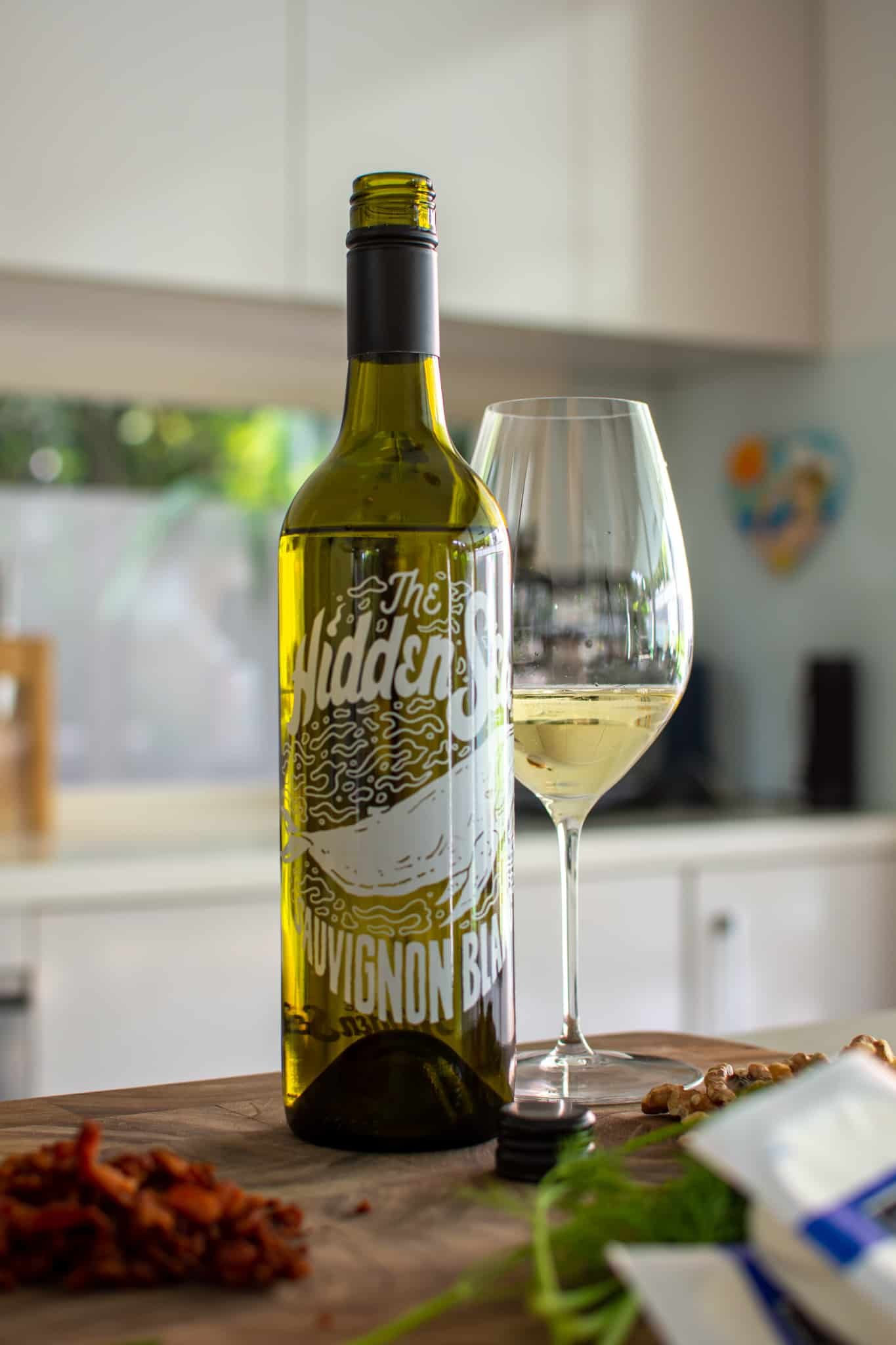 bottle of wine in the kitchen on a chopping board with food beside it 
