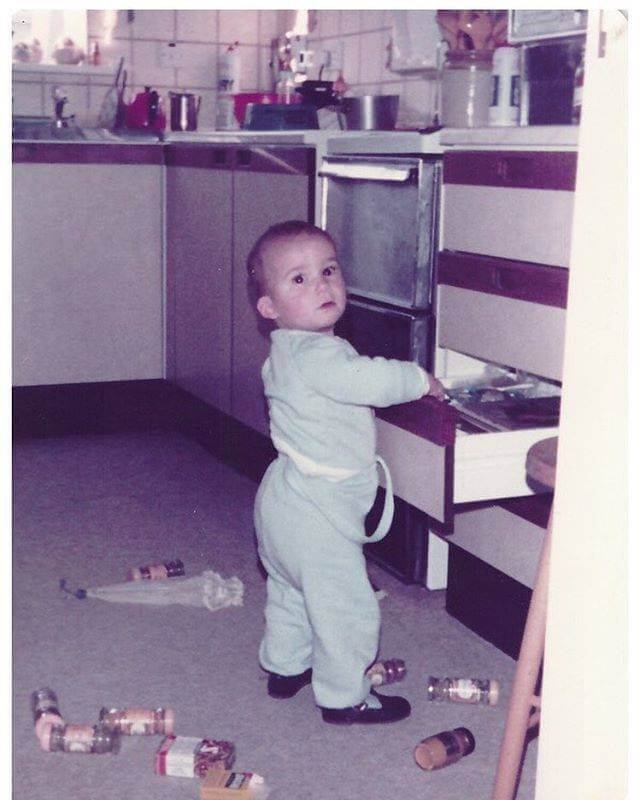 a child in the kitchen playing with food from the drawers in a kitchen