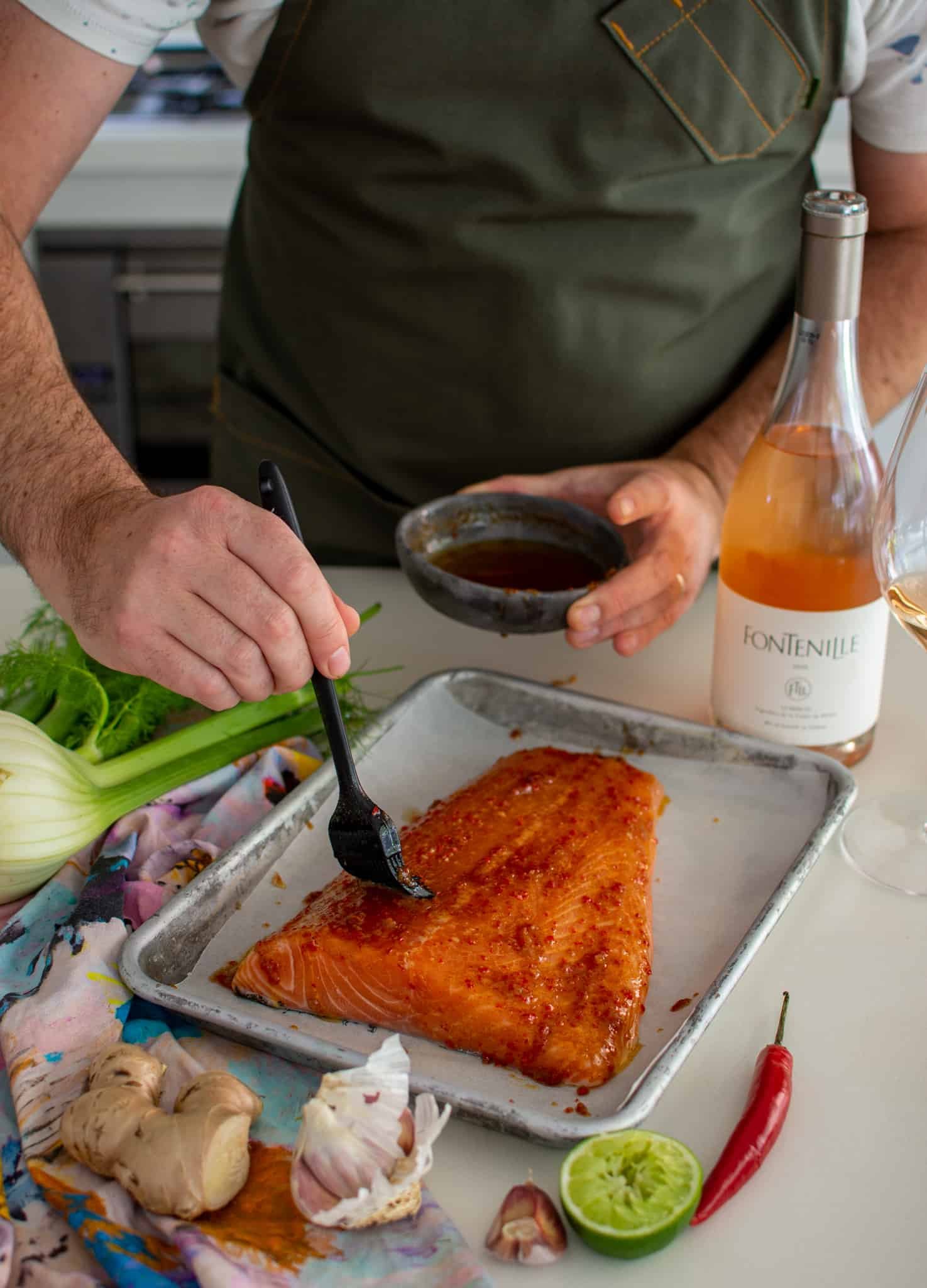someone glazing baked salmon in the kitchen