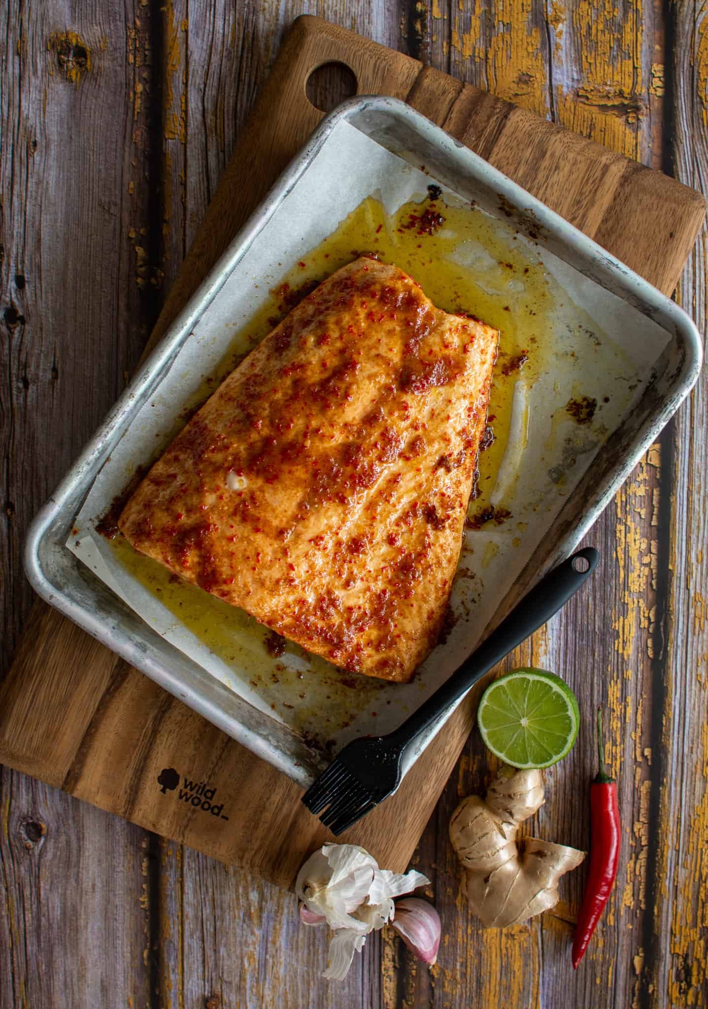 birdseye view of a baked salmon on a baking tray that has been glazed with brown butter, maple, lime & chilli