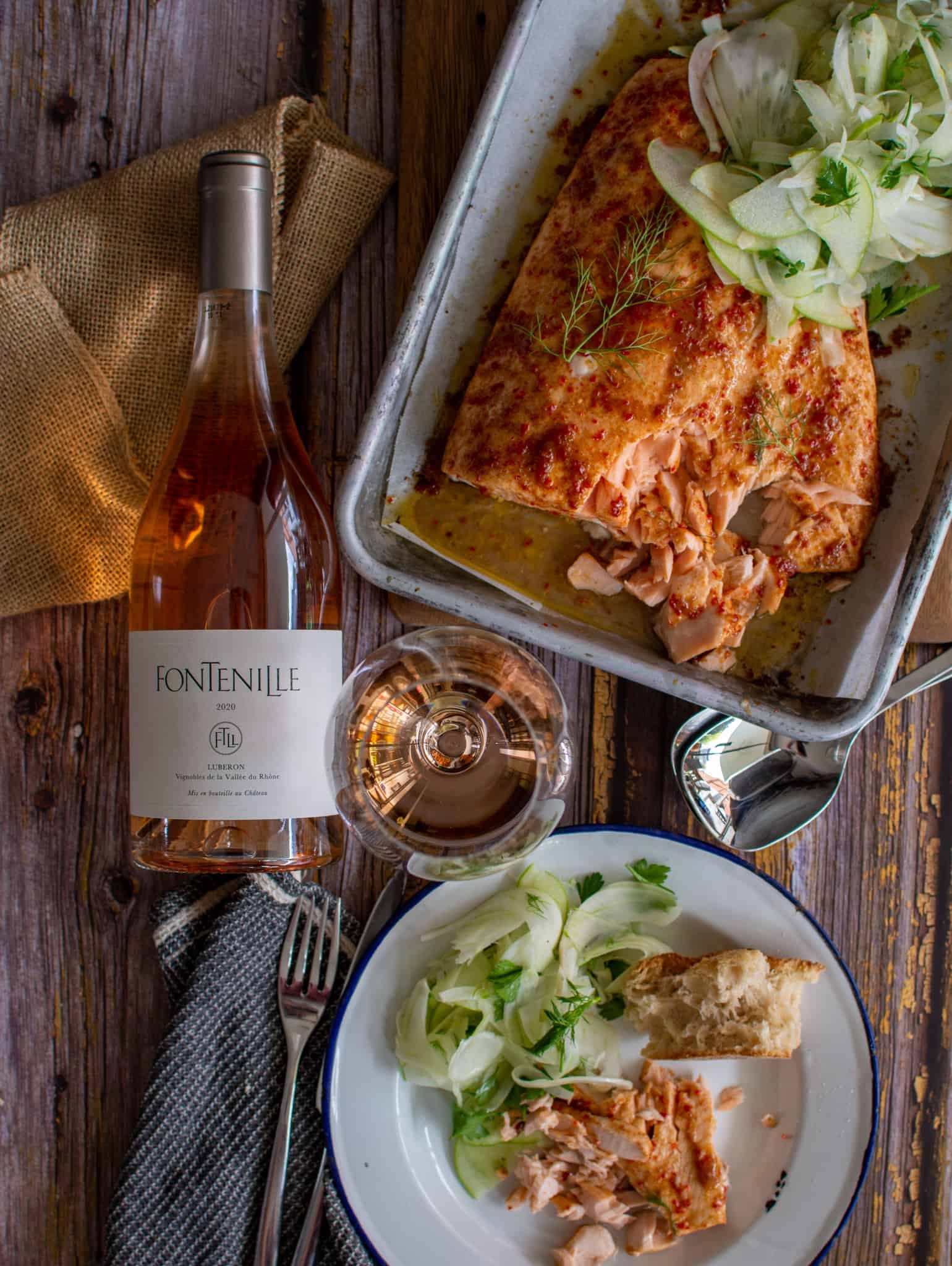 Birdseye view of table setting including maple glazed baked salmon, fontenille rose, wine glass and  a plate with salmon on it 
