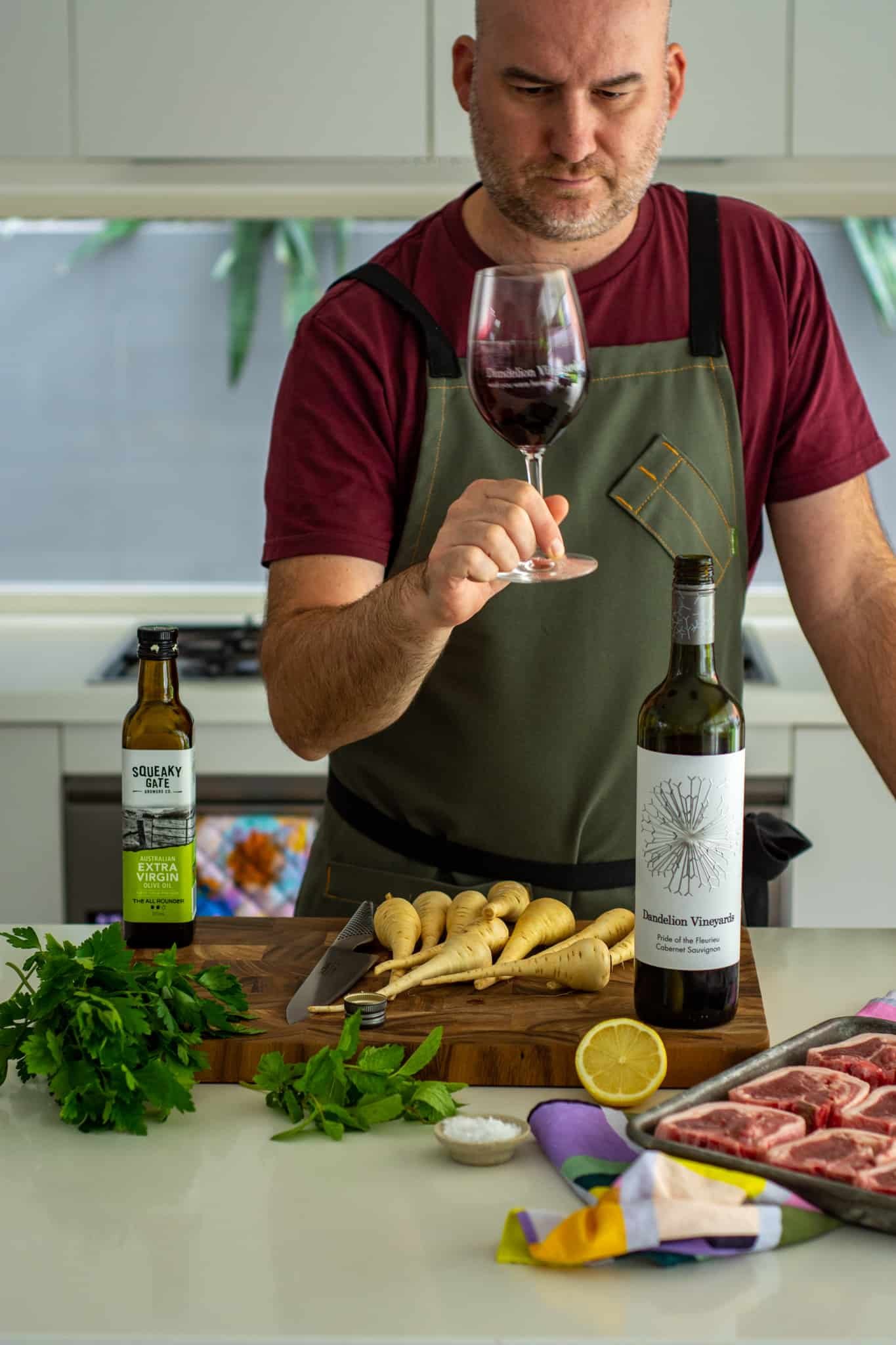 someone swirling wine in a glass with food on the kitchen counter top