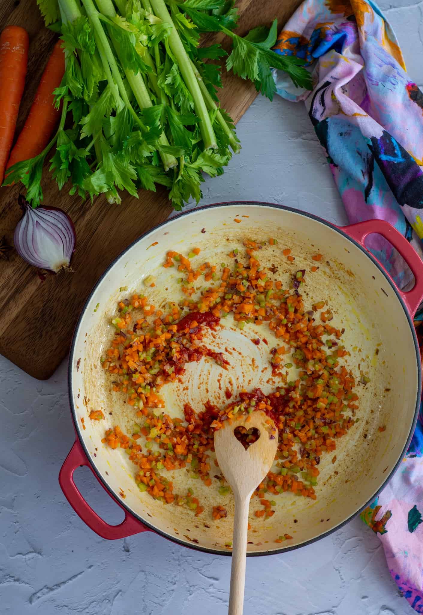 Tomato paste being stirred into hot pan with vegetables 