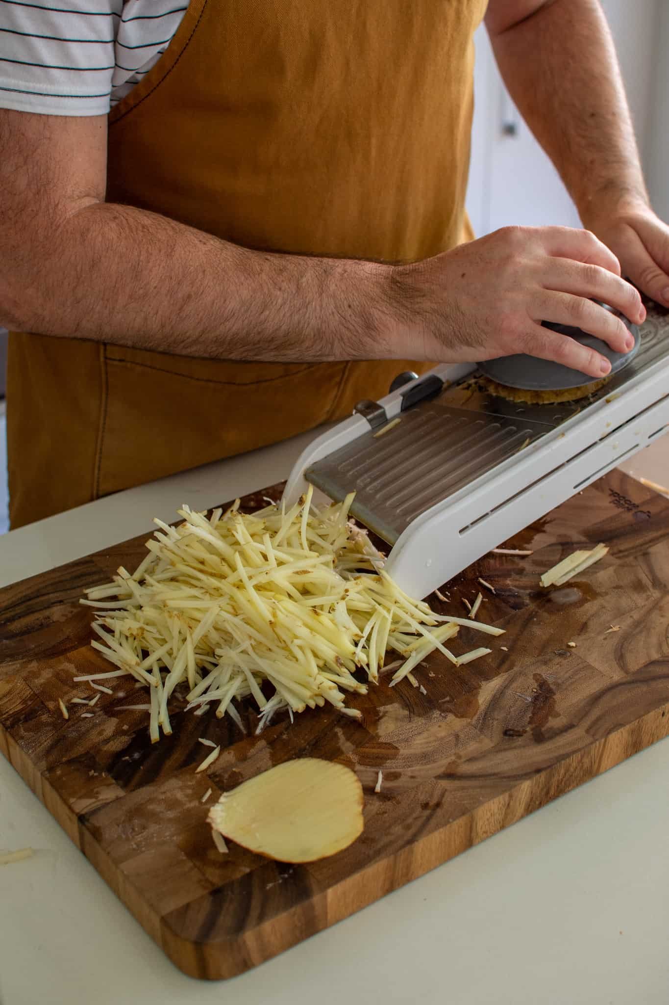 someone slicing potatoes on a mandoline