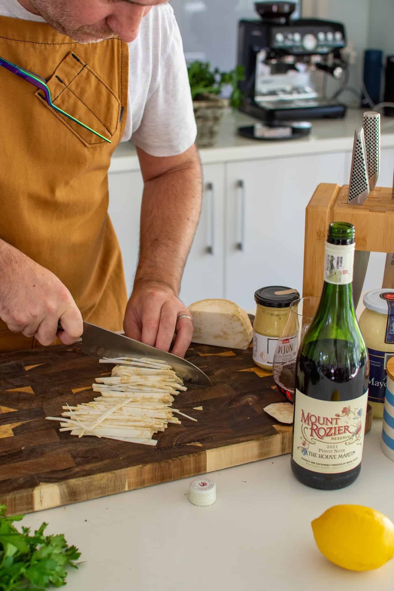 Slicing celeriac with wine and other food beside the chopping board