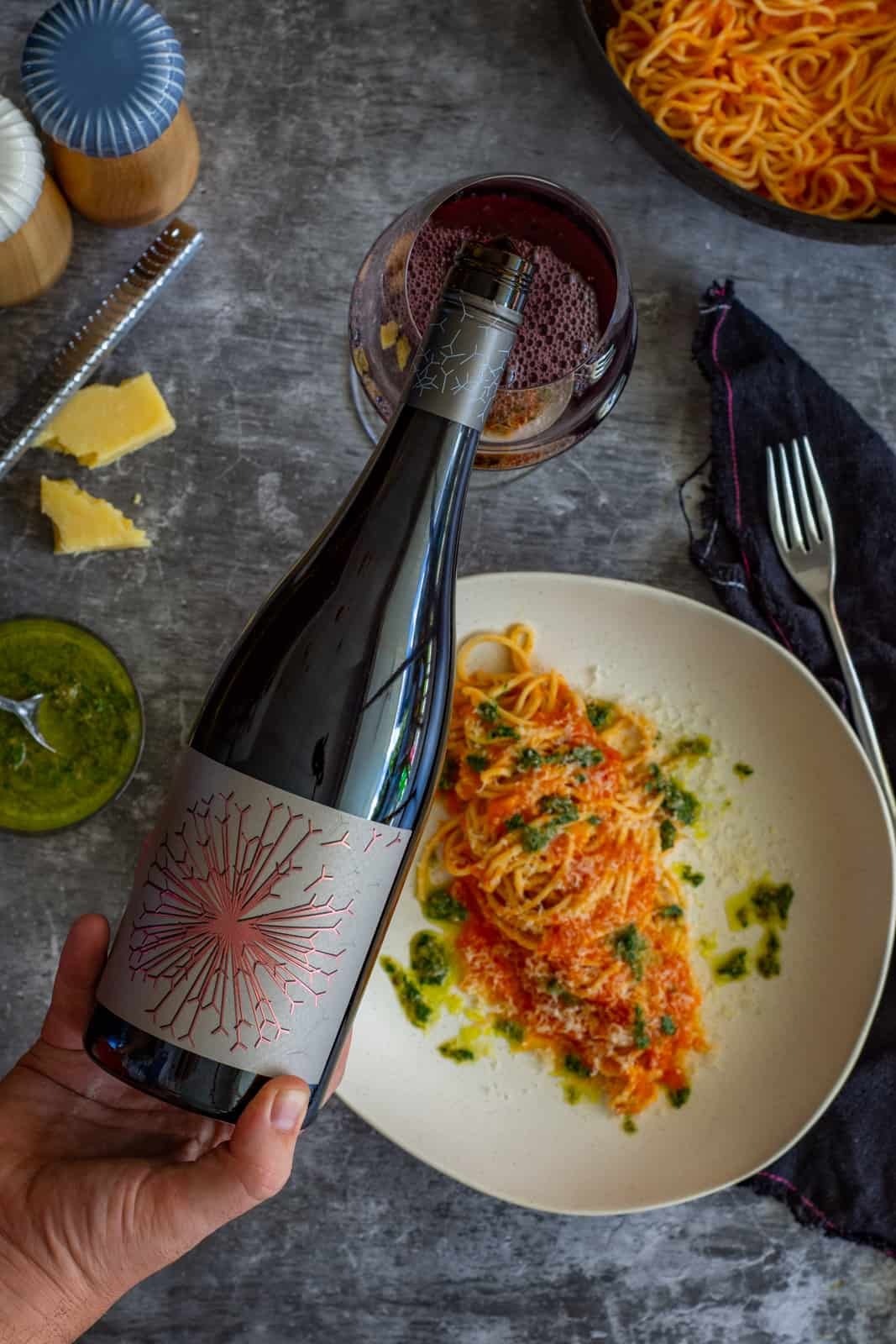 Someone is pouring a glass of Dandelion Grenache wine with a bowl of pasta below 